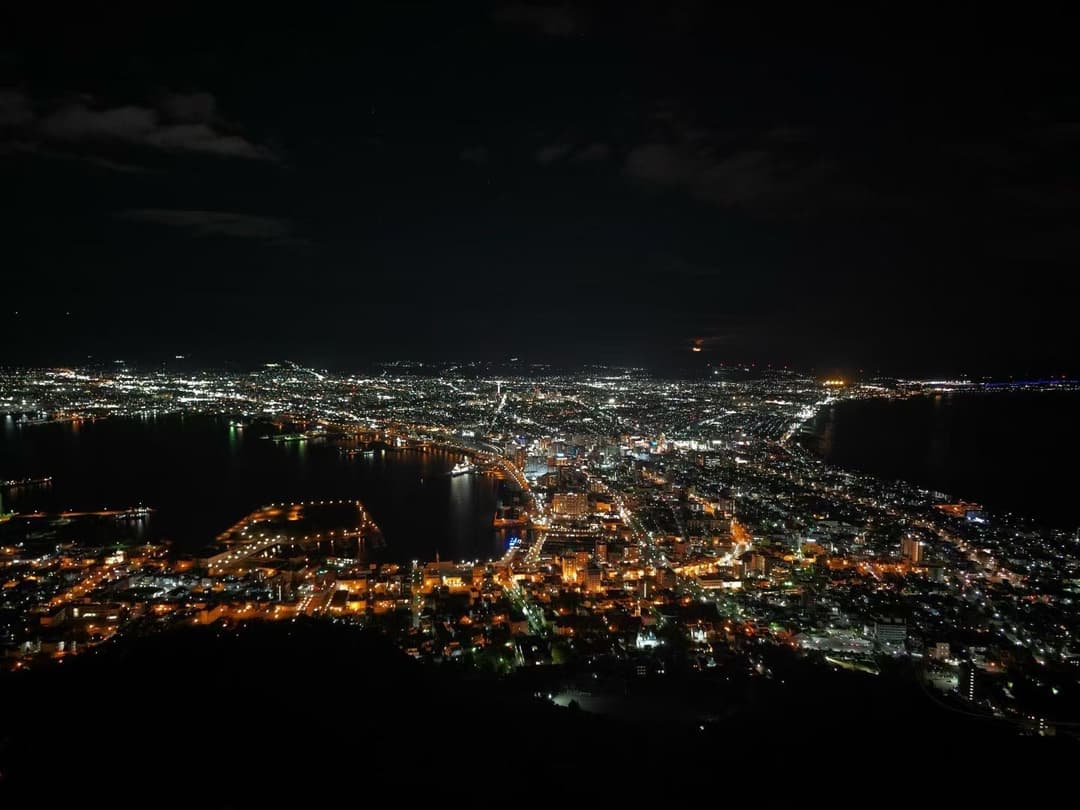从函馆山俯瞰函馆夜景，城市灯火夹在两片海湾之间
