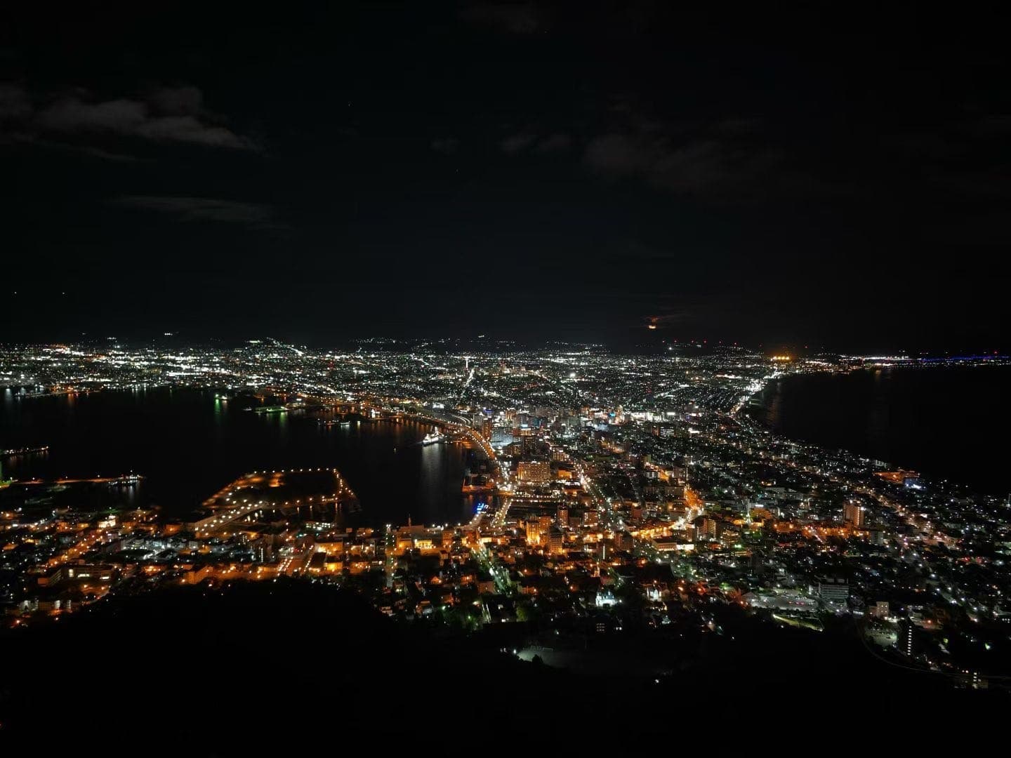 从函馆山俯瞰函馆夜景，城市灯火夹在两片海湾之间