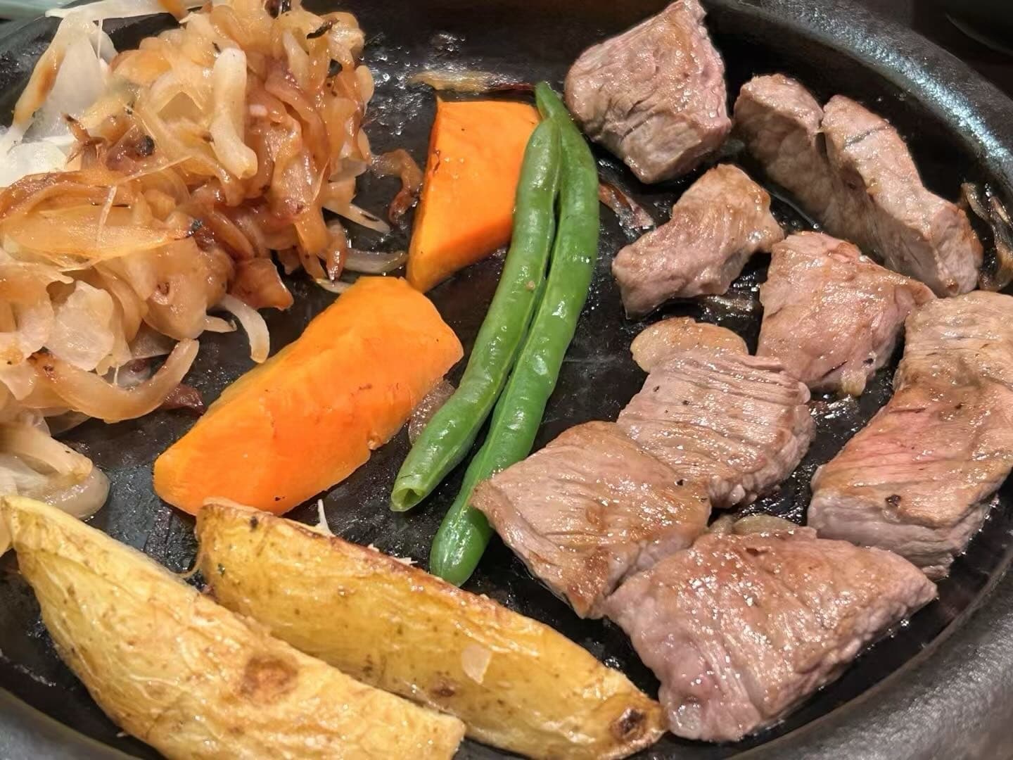 铁板上的神户牛肉块、洋葱和蔬菜