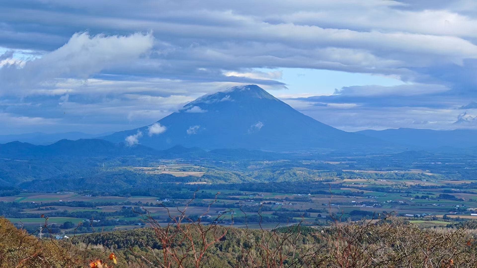 远处羊蹄山在北海道平原和云层之间露出轮廓