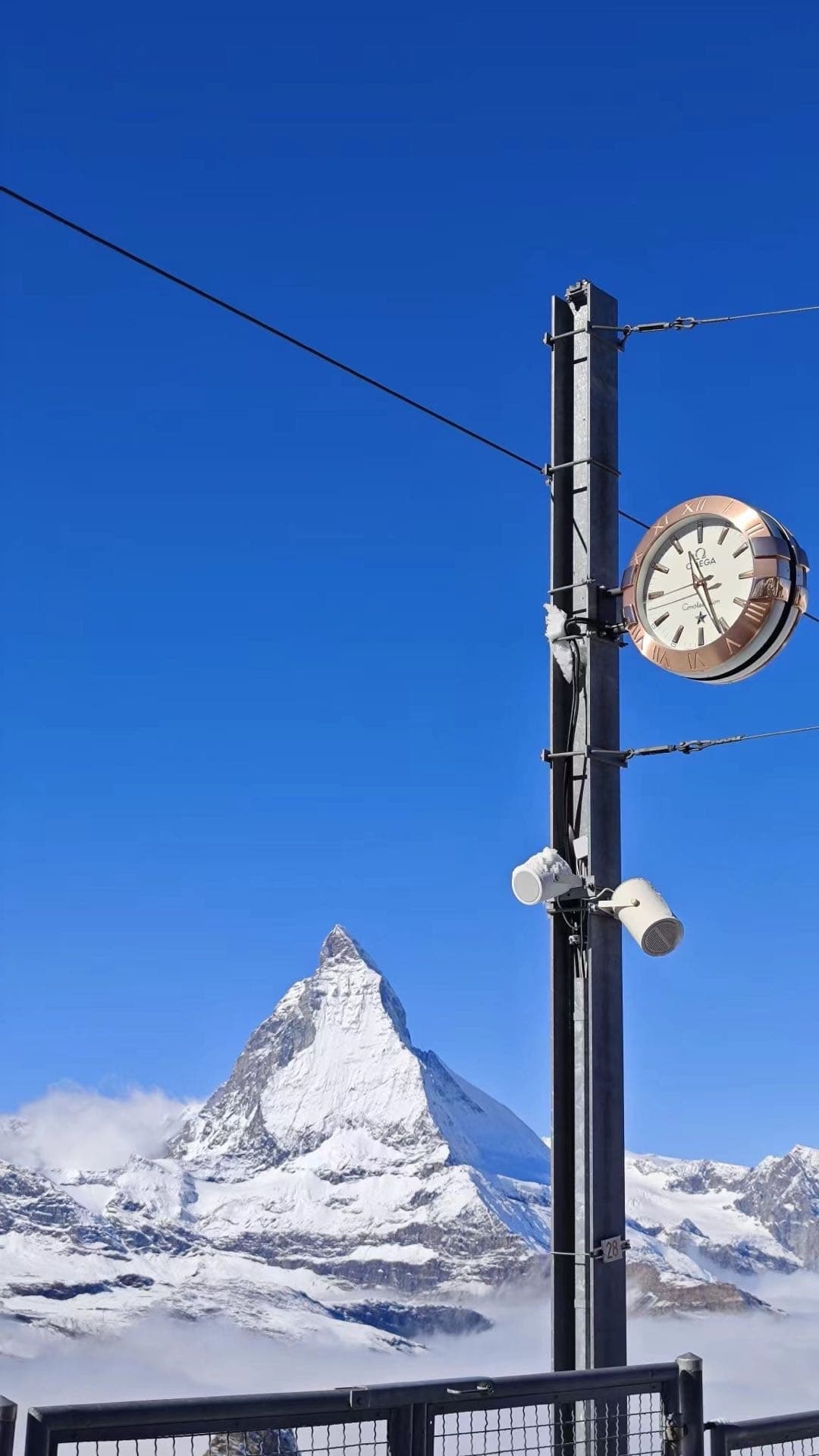 马特洪峰远处雪山与平台上的时钟立杆