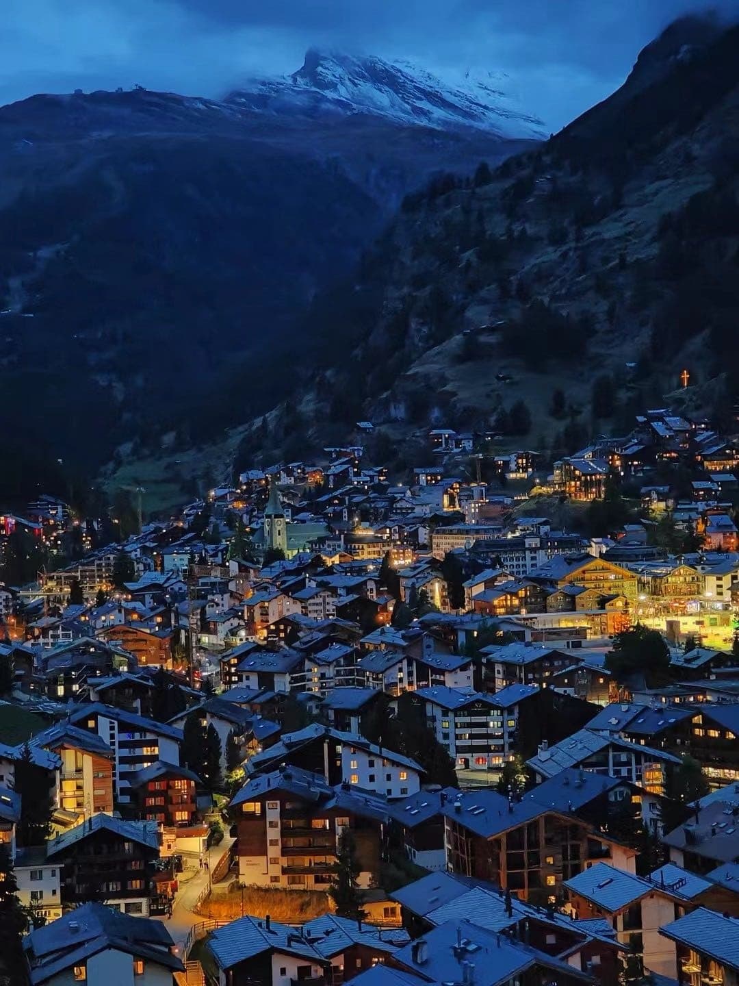夜色中的采尔马特小镇灯火，远处山体隐在蓝黑色背景里