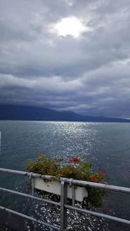 阴云下的日内瓦湖面，阳光在远处水面上反光