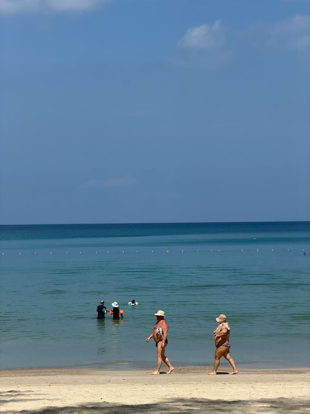 普吉岛浅海边行走的游客