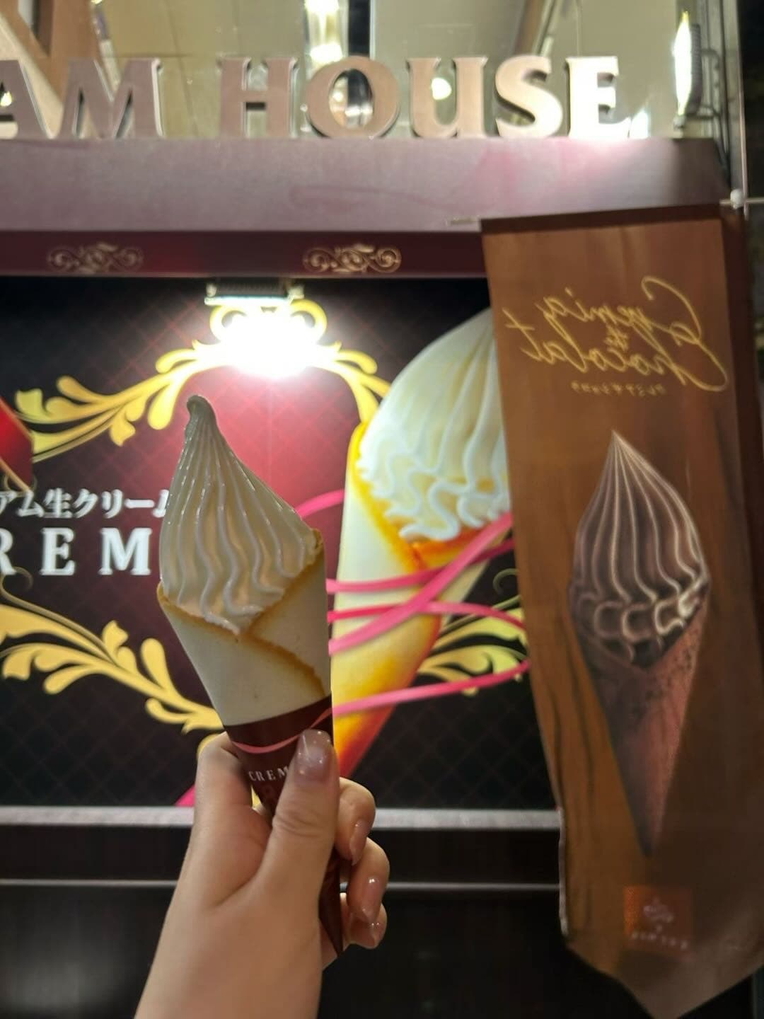 手拿两支冰淇淋，背景是甜品店招牌