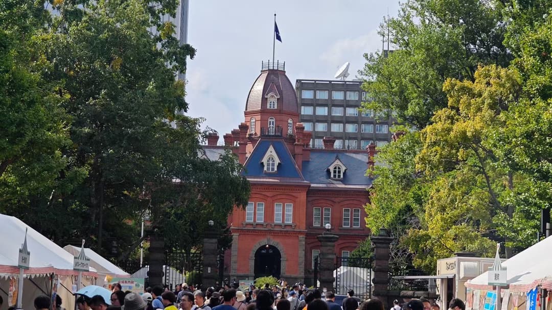 白色恋人公园红砖建筑和尖顶屋面前有游客与摊位